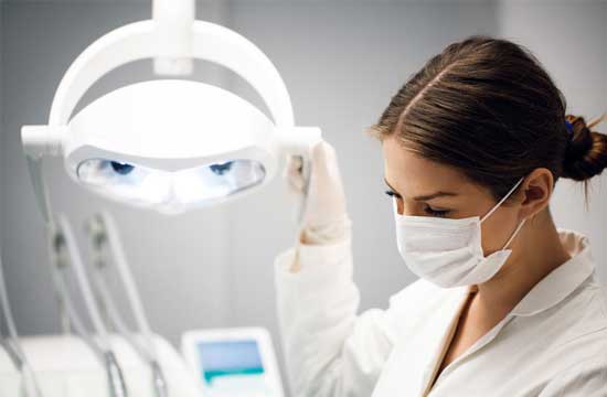 Female dentist adjusting illuminated lamp in clinic