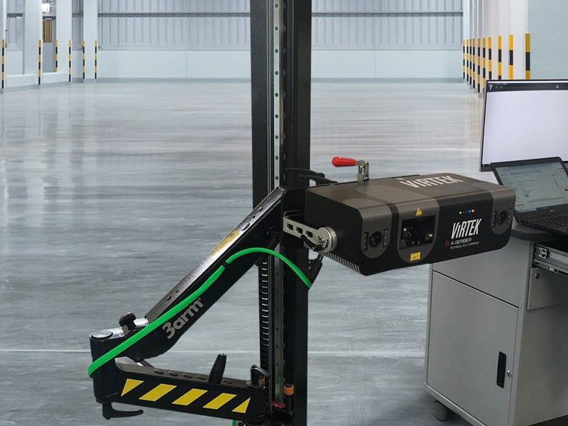 A black robotic arm with sensors in a warehouse, scanning the environment.