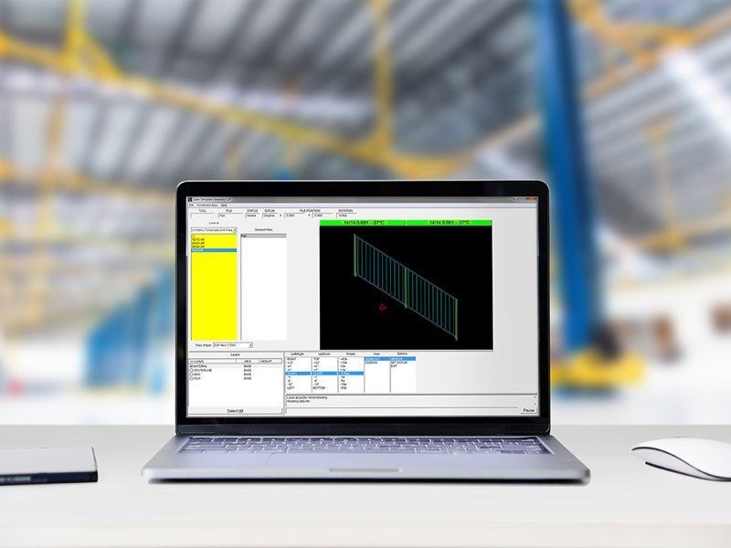 Laptop displaying software with a green-lined diagram, in a warehouse setting.