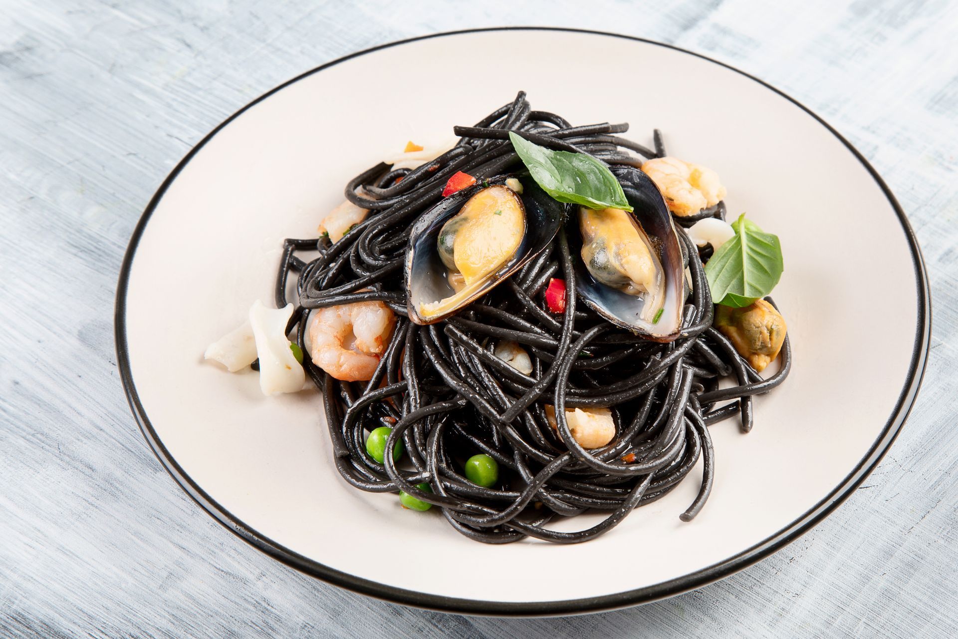 Un piatto di spaghetti neri con gamberi e cozze su un tavolo.