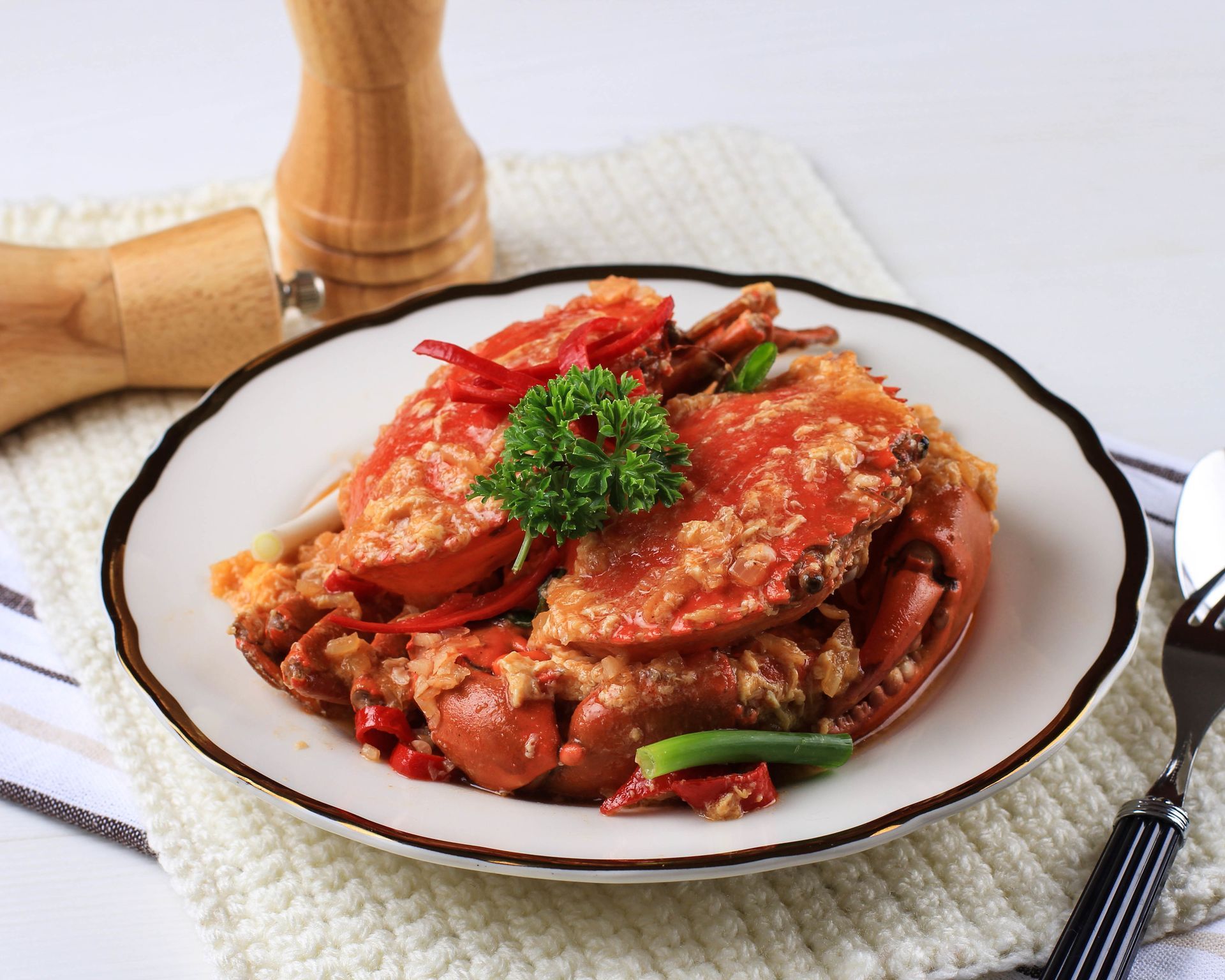 Un piatto bianco condito con granchio e verdure su un tavolo.