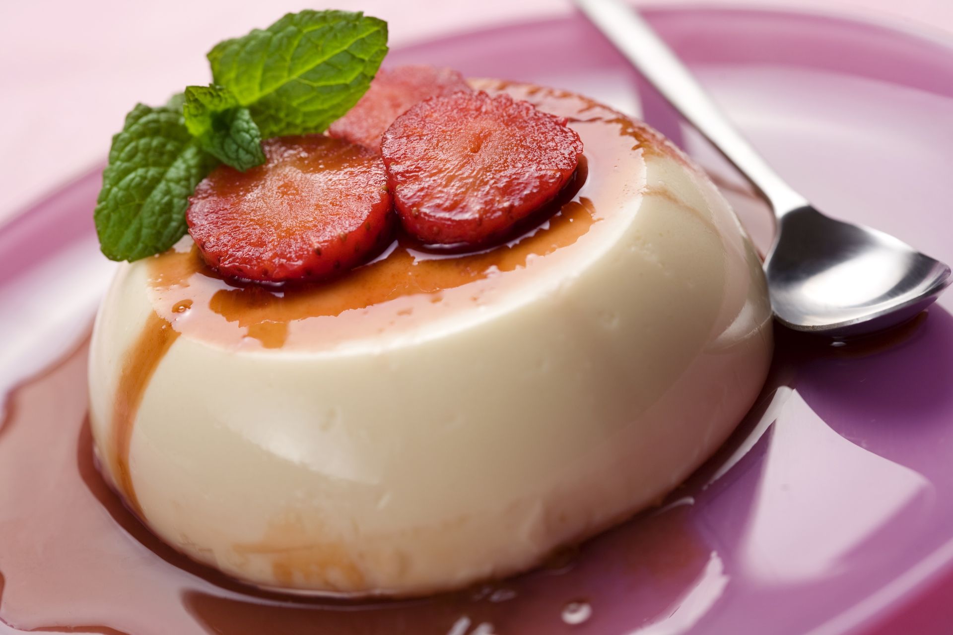 Un dessert con sopra le fragole su un piatto con un cucchiaio.