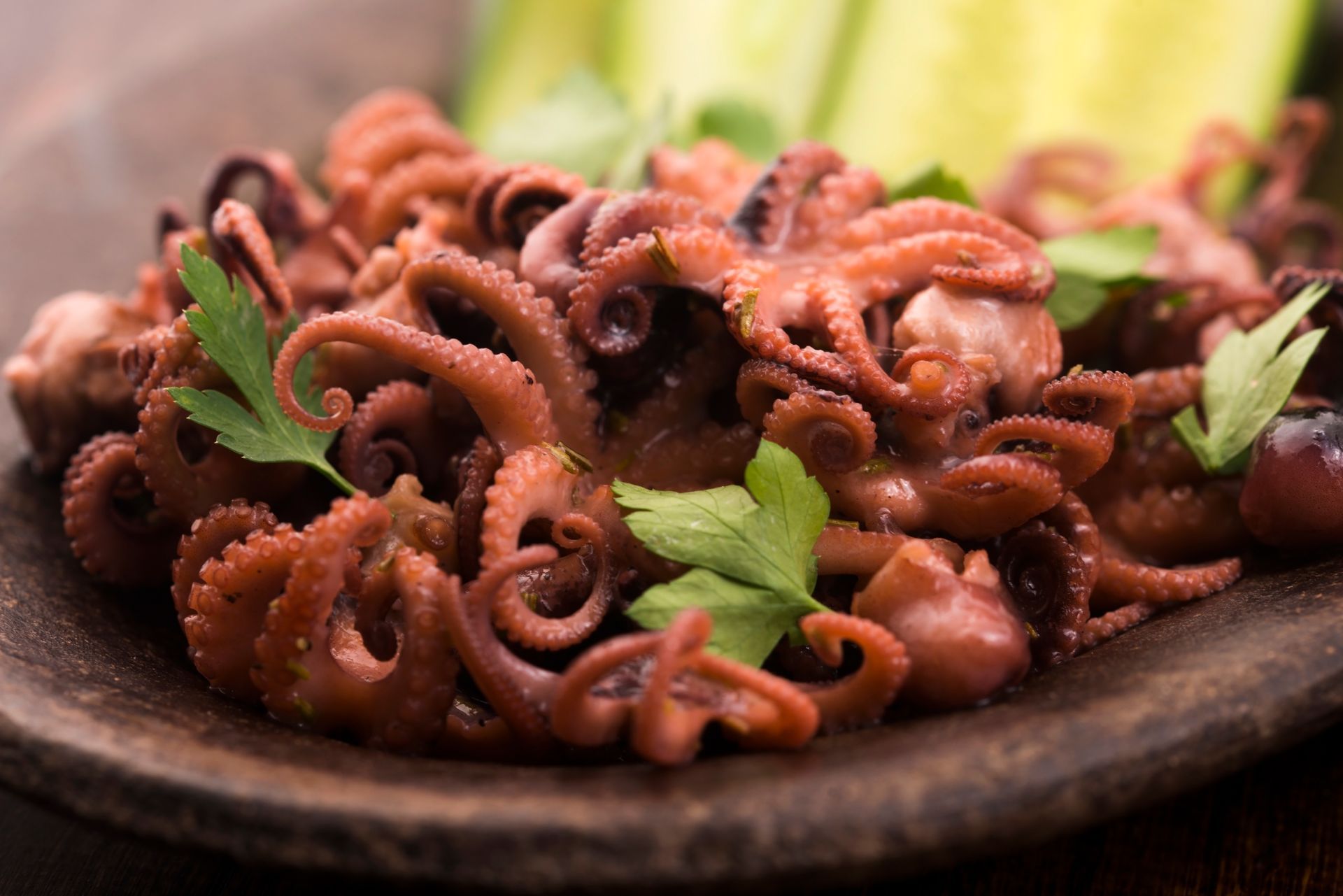 Un piatto di polpo cotto con prezzemolo su un tavolo di legno.