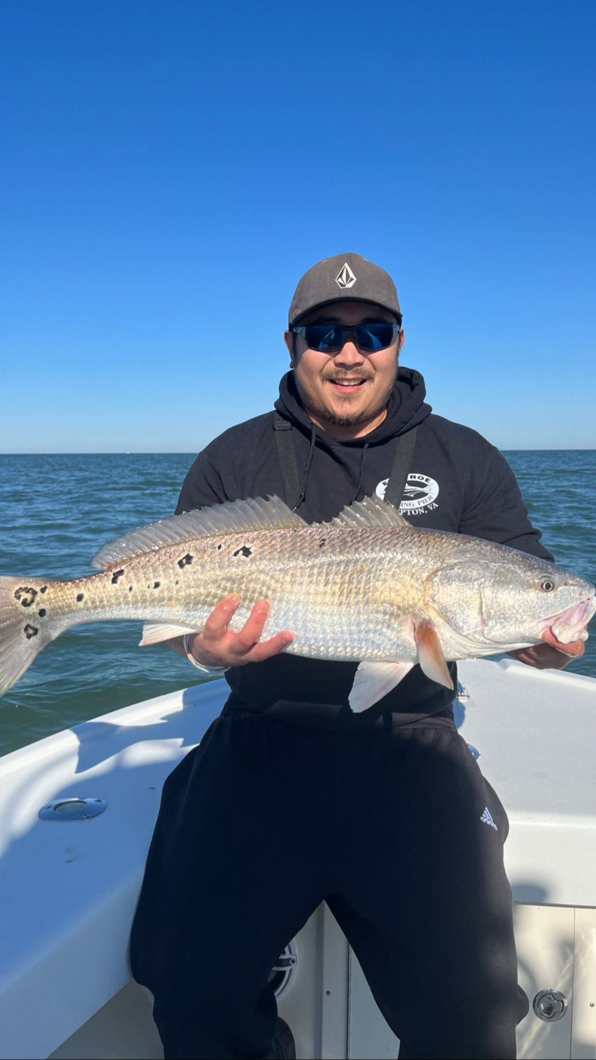 A man is sitting on a boat holding a large fish.