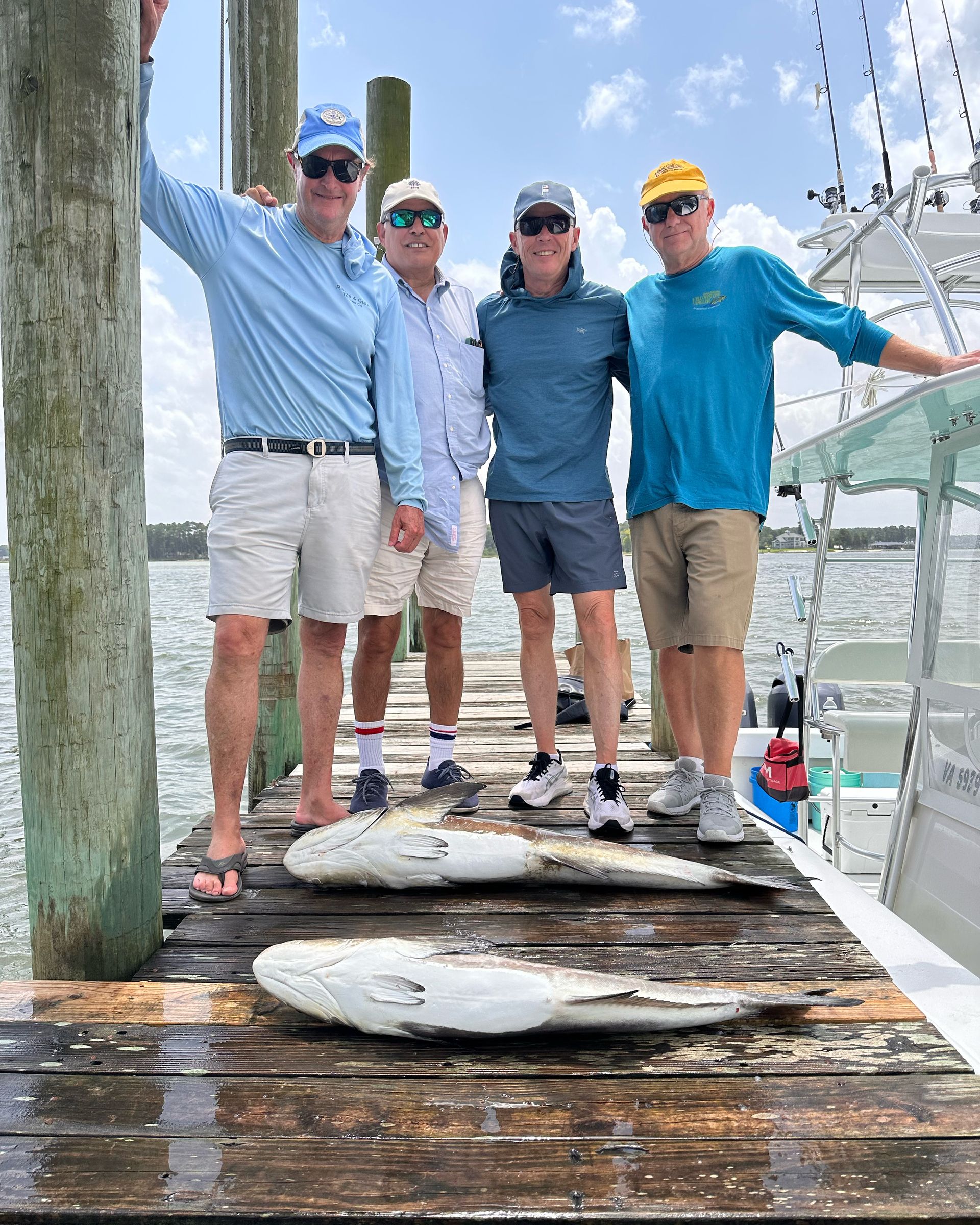 A group of men are posing for a picture on a dock with fish.