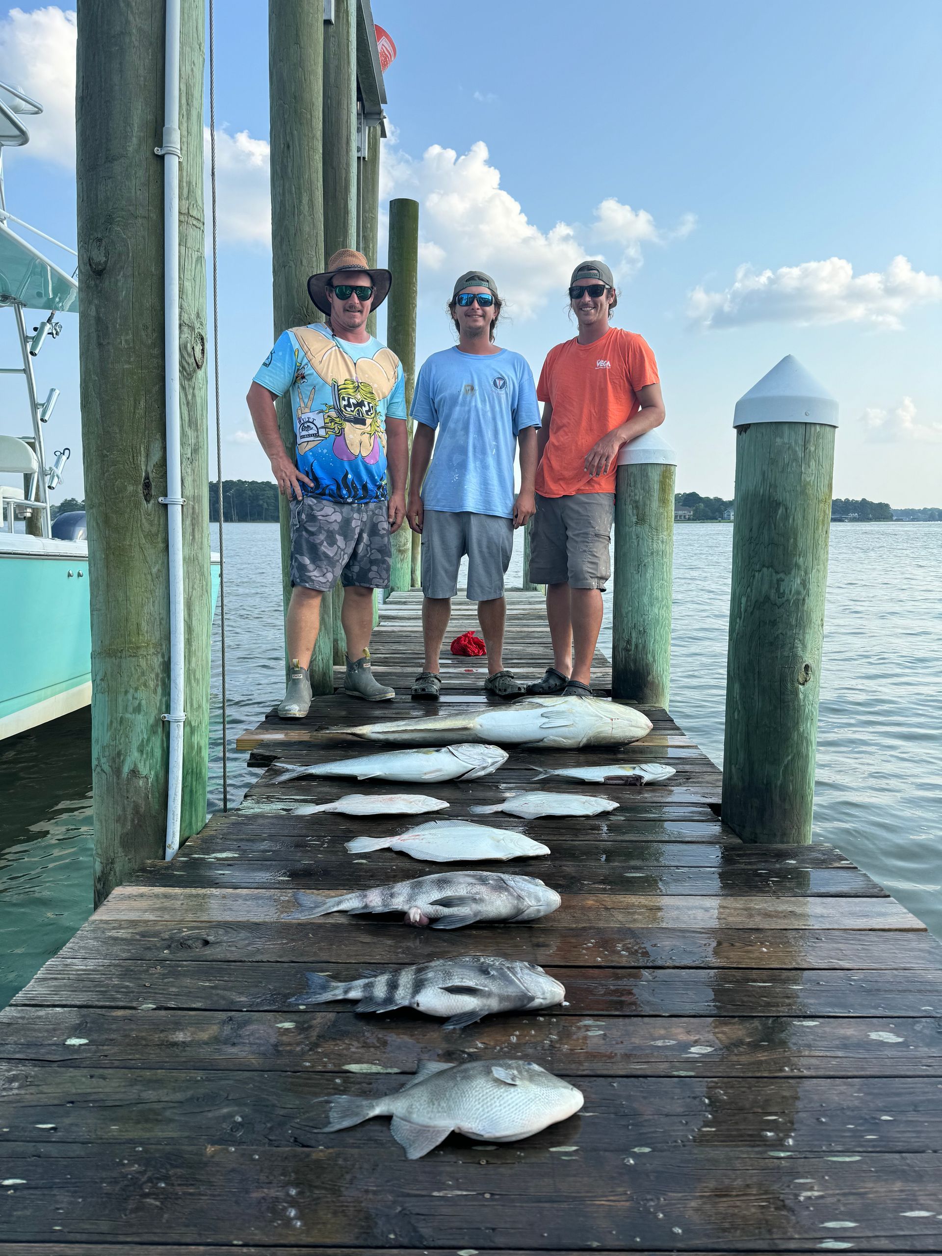 Three men are standing on a dock with fish on it.