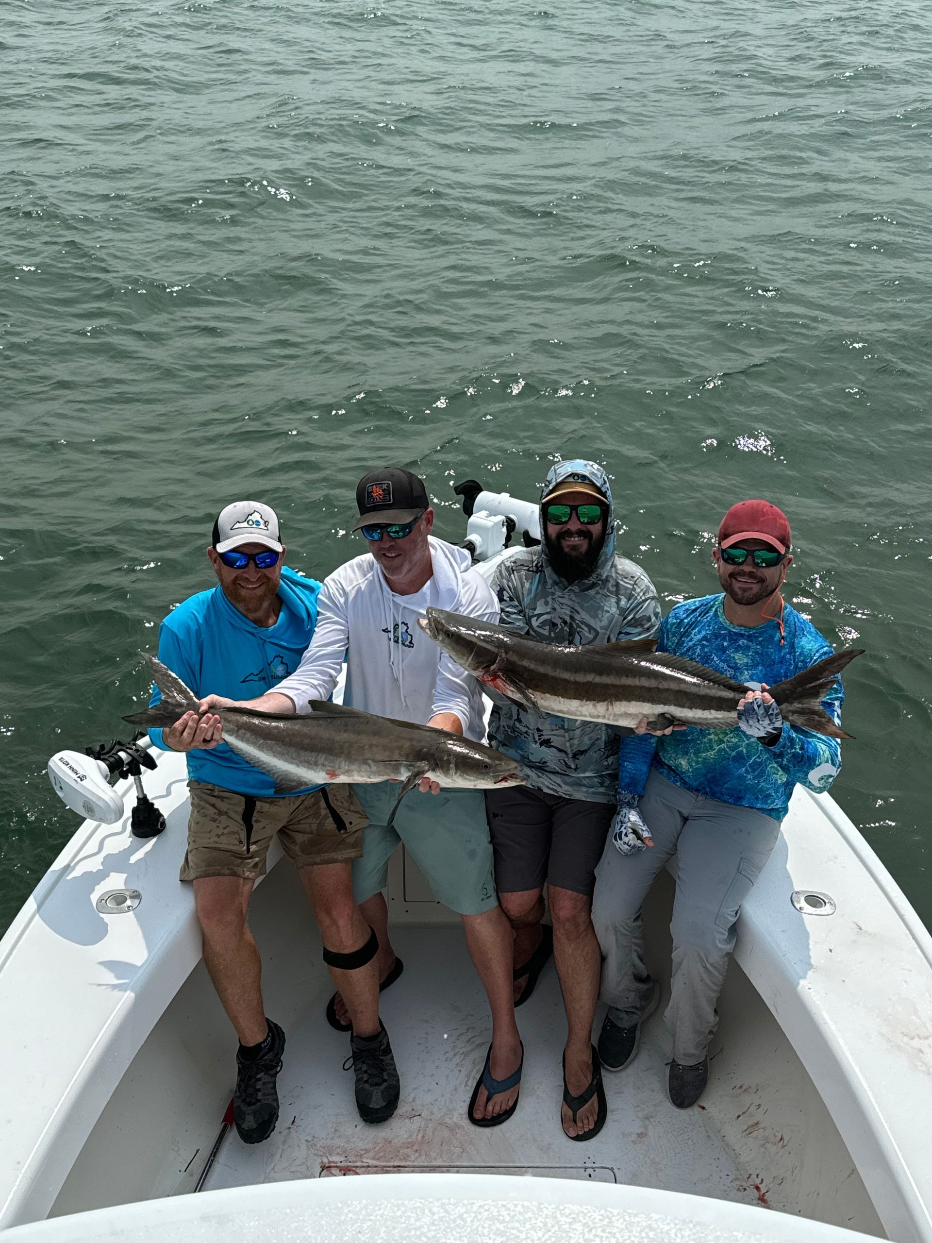 A group of men are standing on a boat holding fish.
