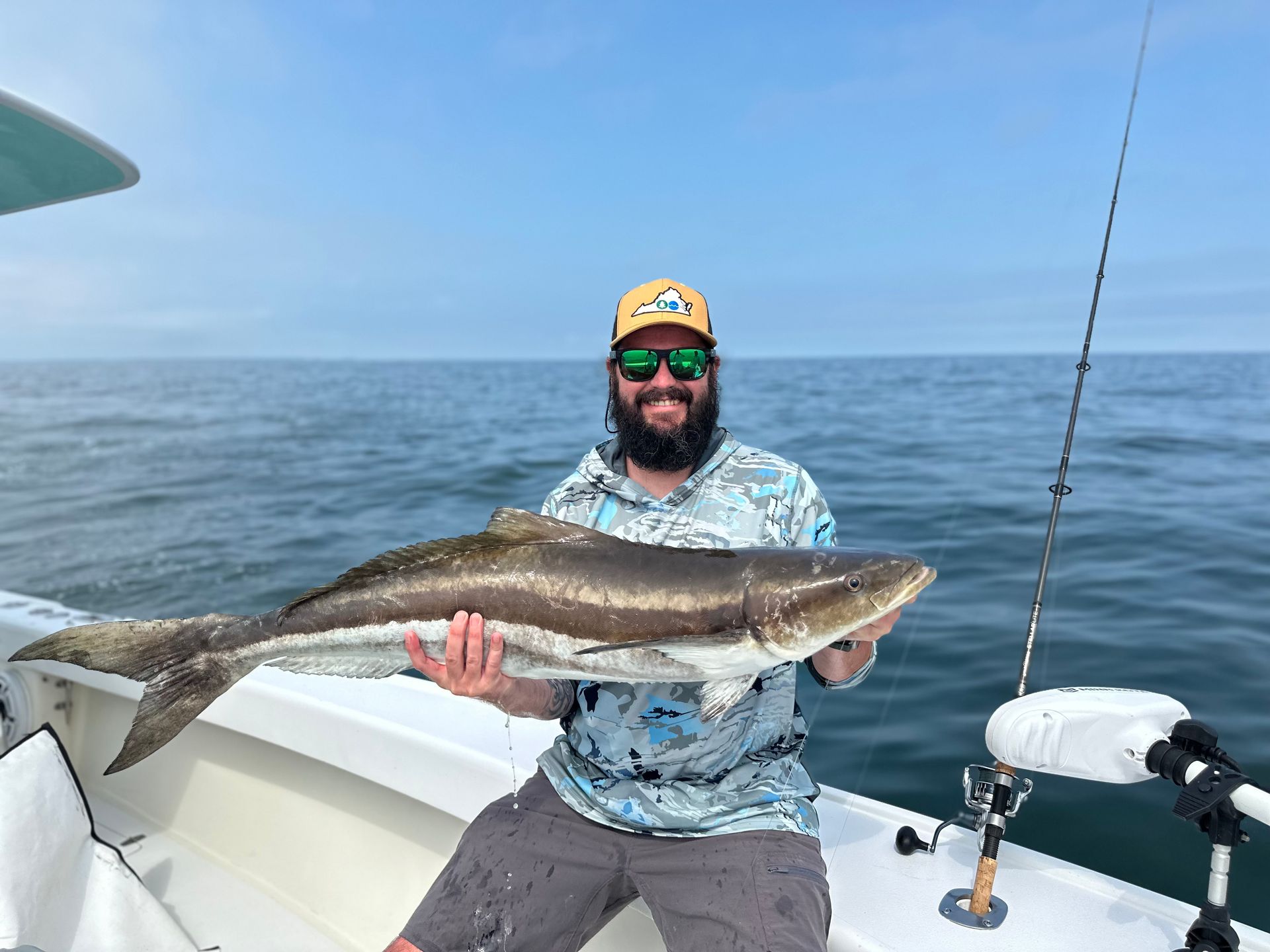 A man is holding a large fish on a boat in the ocean.