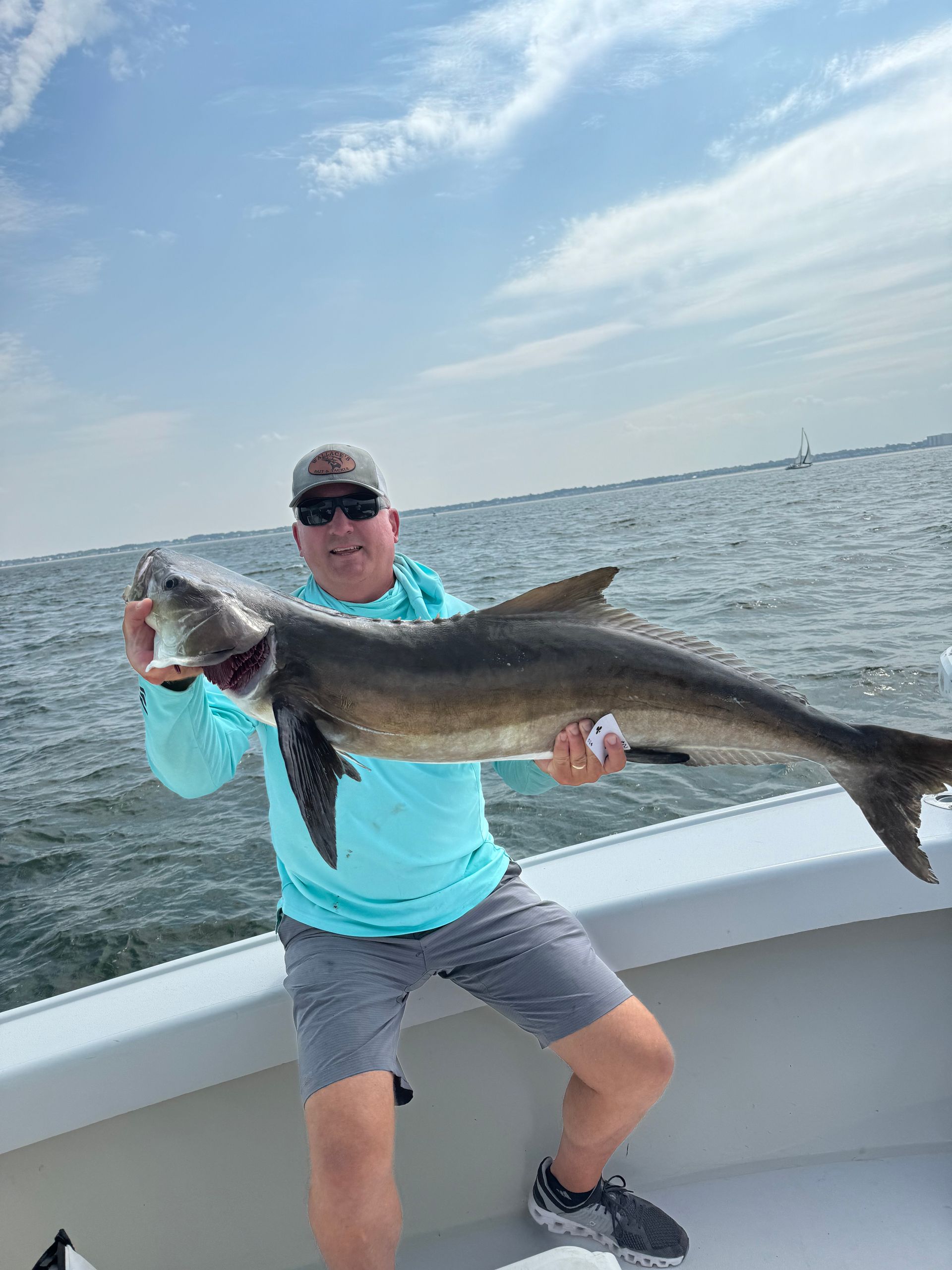A man is holding a large fish on a boat.