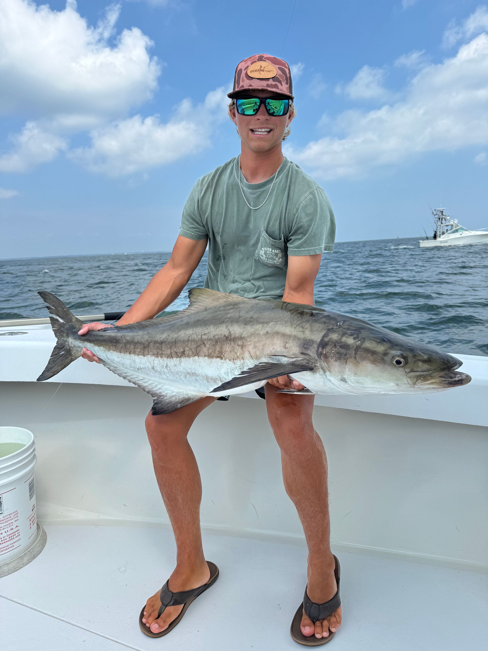 A man is sitting on a boat holding a large fish.