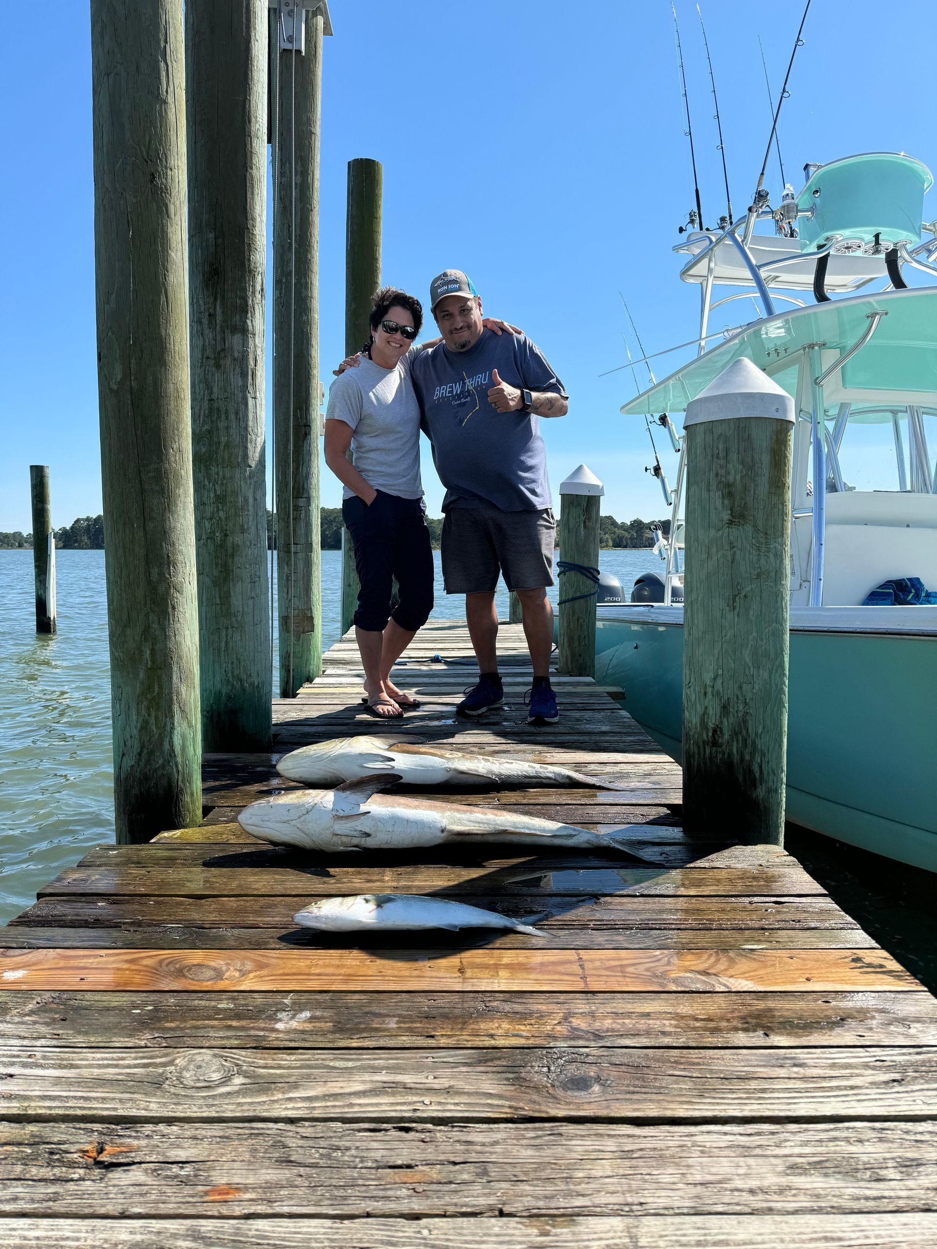 A man and a woman are standing on a dock next to a boat.