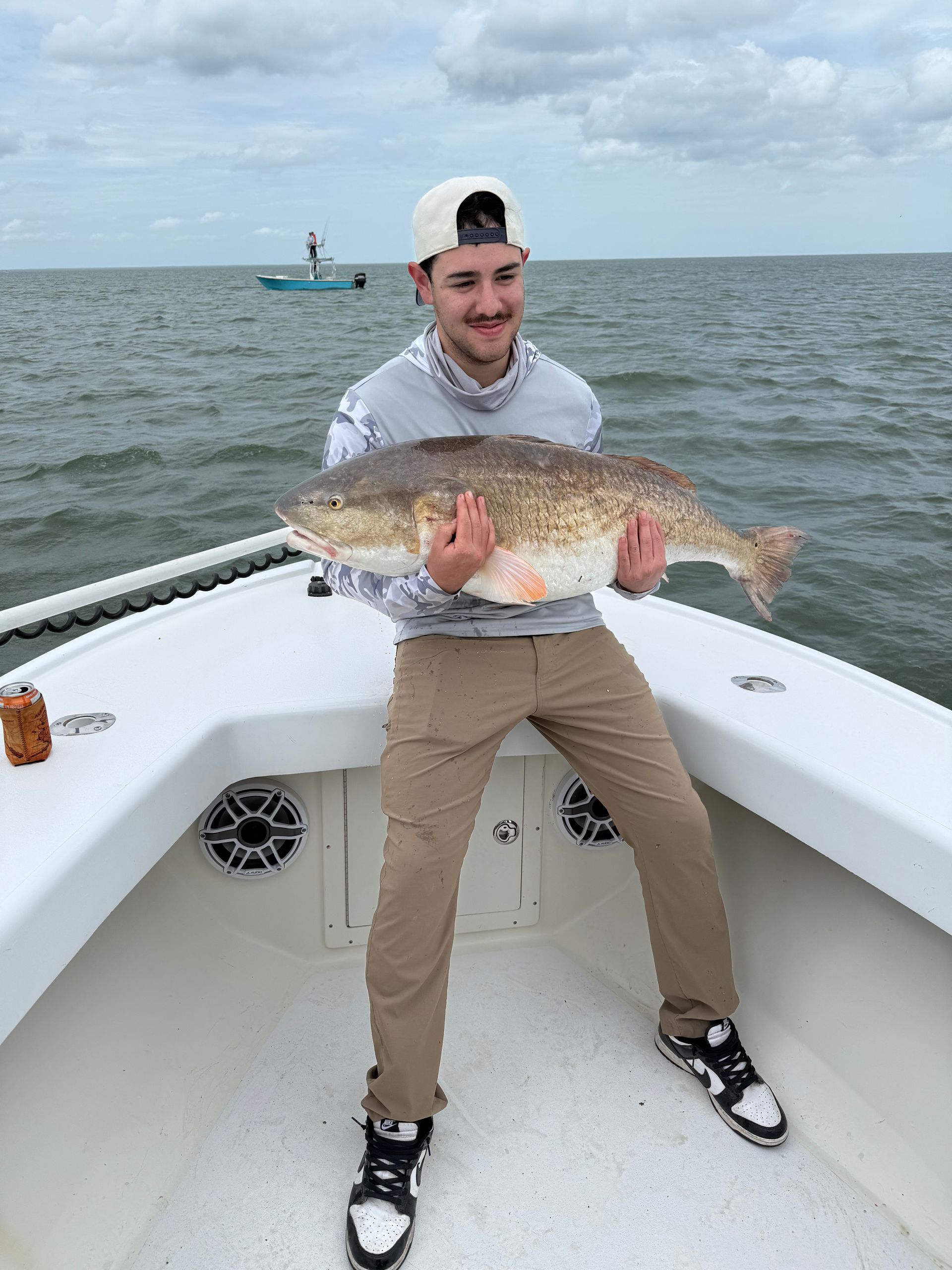 A man is sitting on the front of a boat holding a large fish.