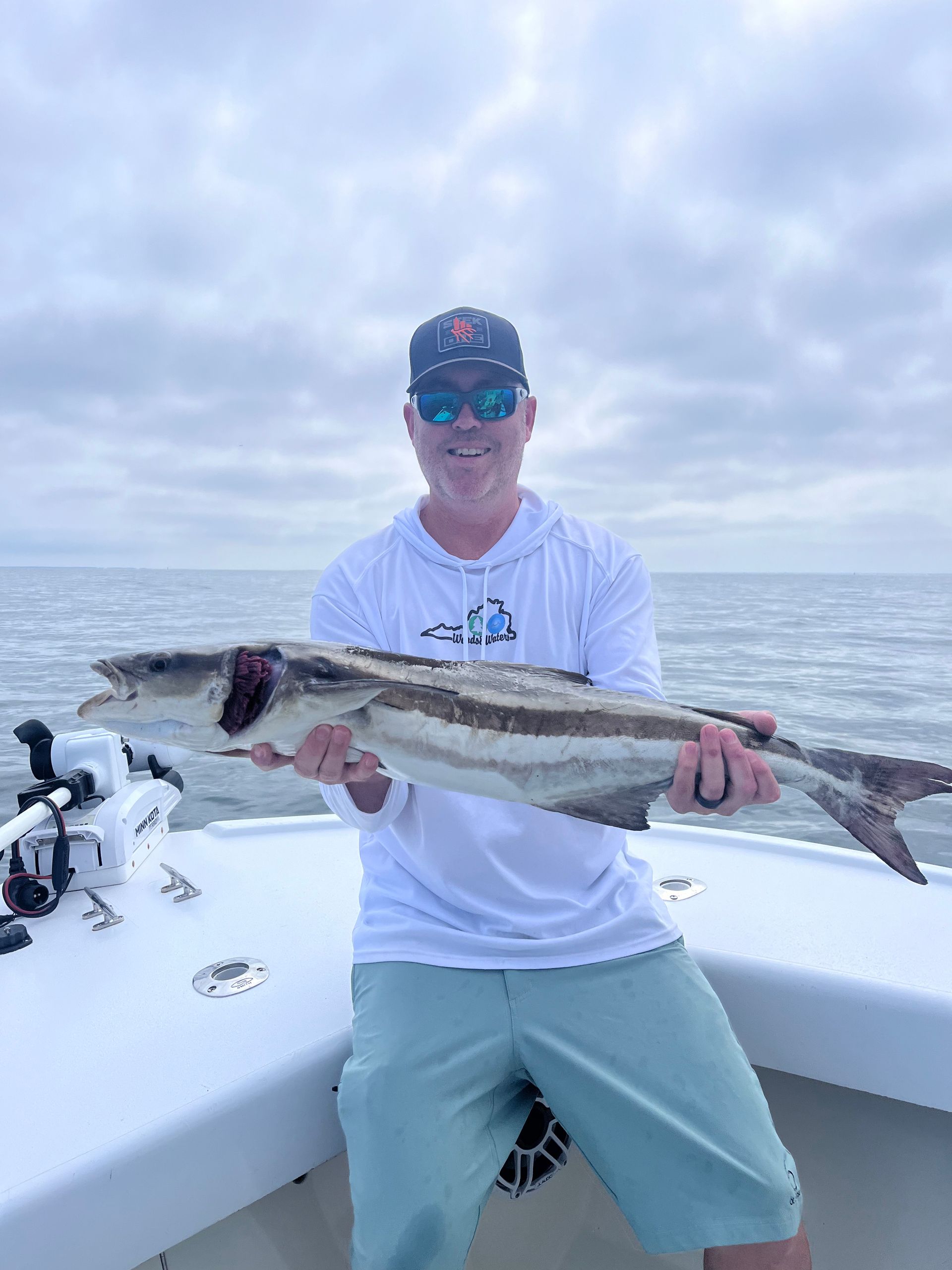 A man is holding a large fish on a boat.