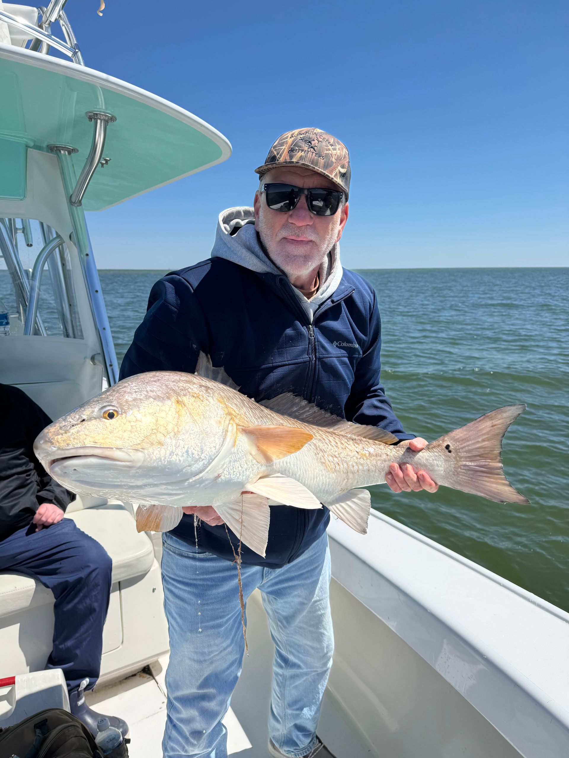 A man is holding a large fish on a boat.