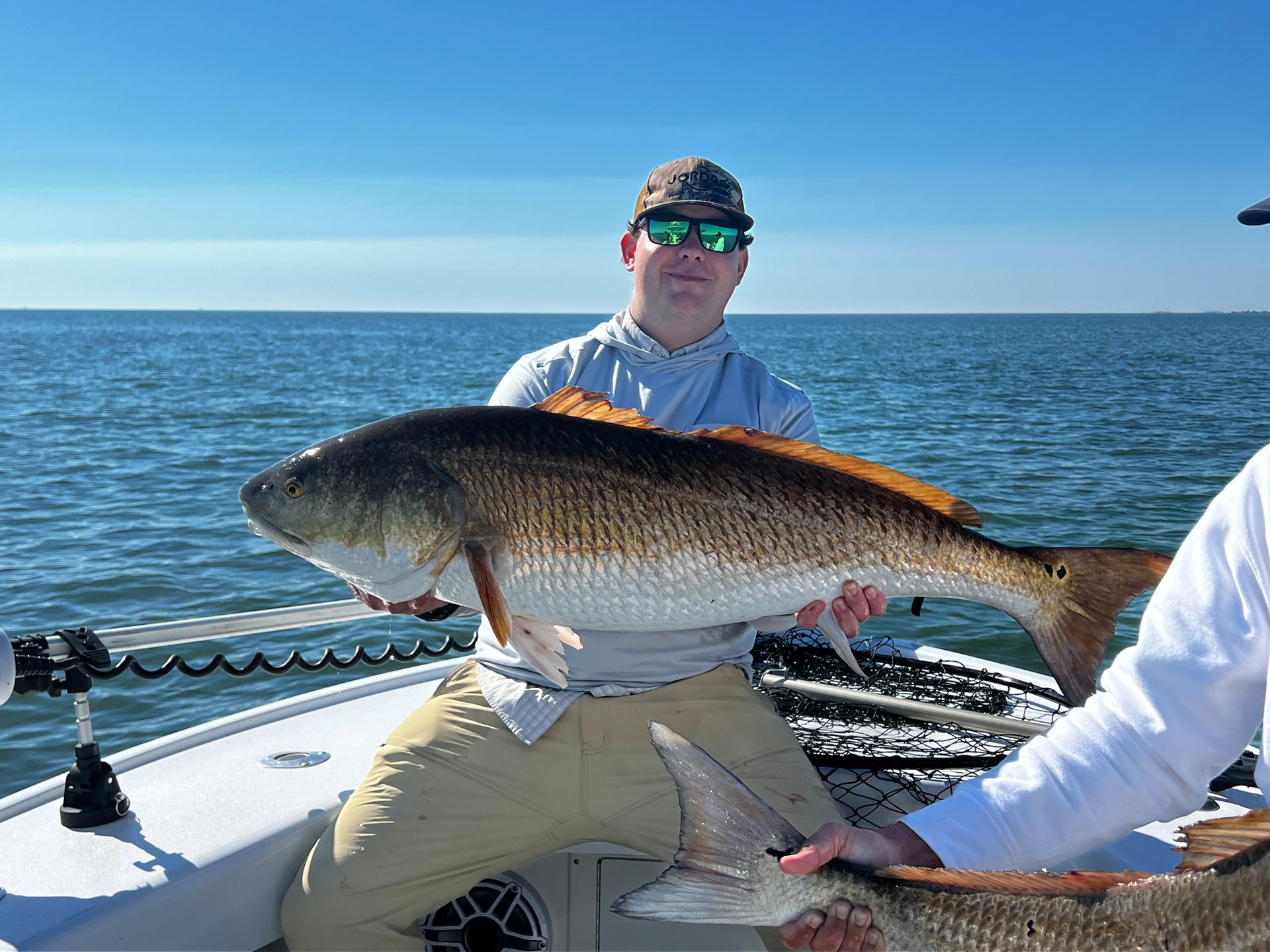 A man is holding a large fish on a boat.