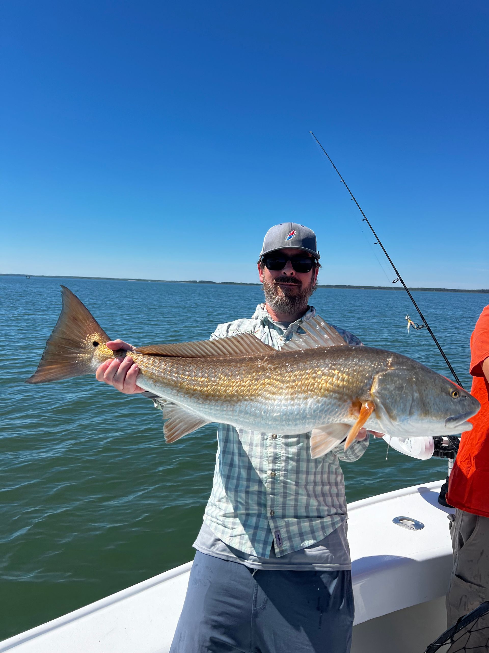 A man is holding a large redfish on a boat.