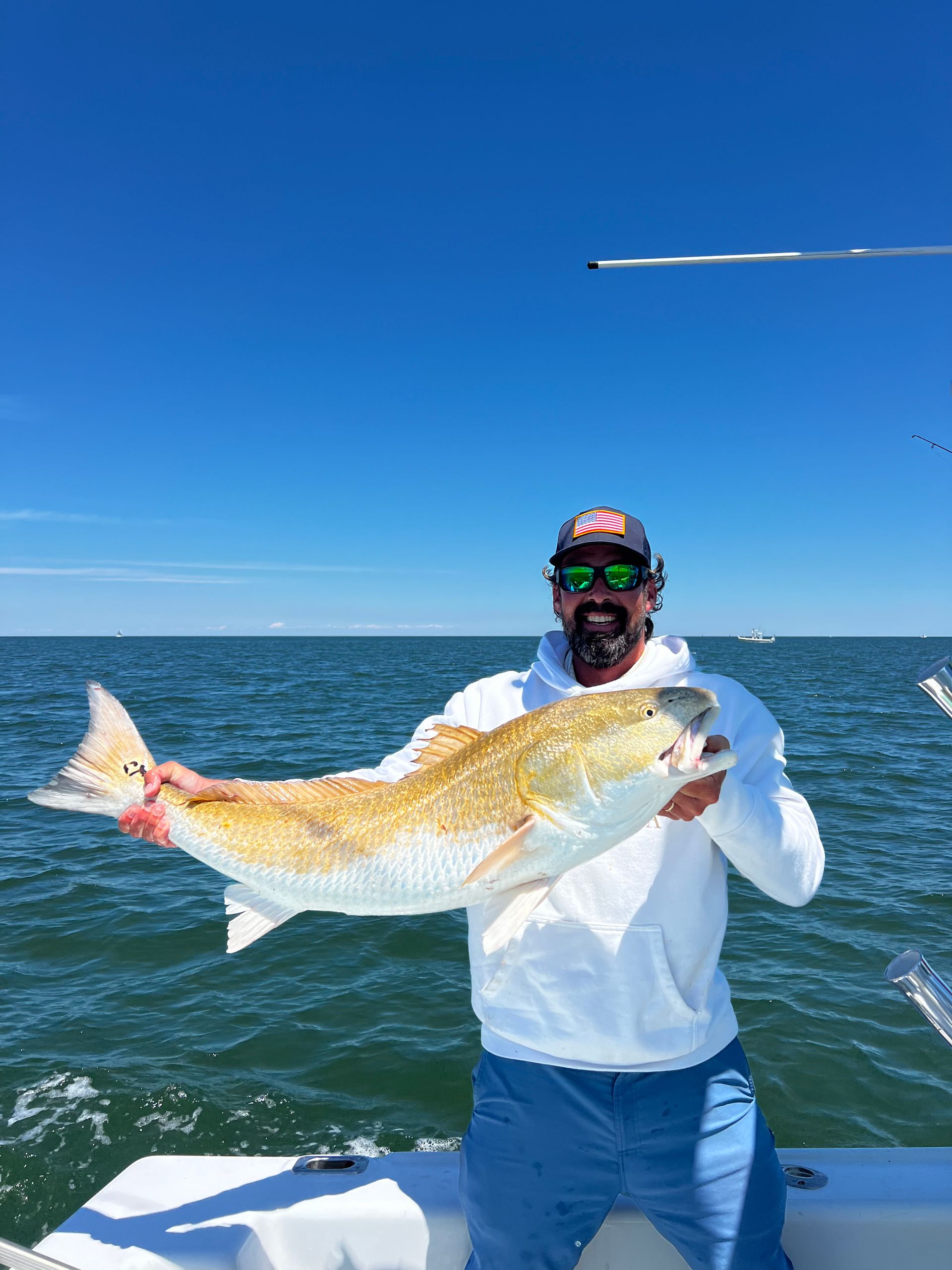 A man is holding a large fish on a boat in the ocean.