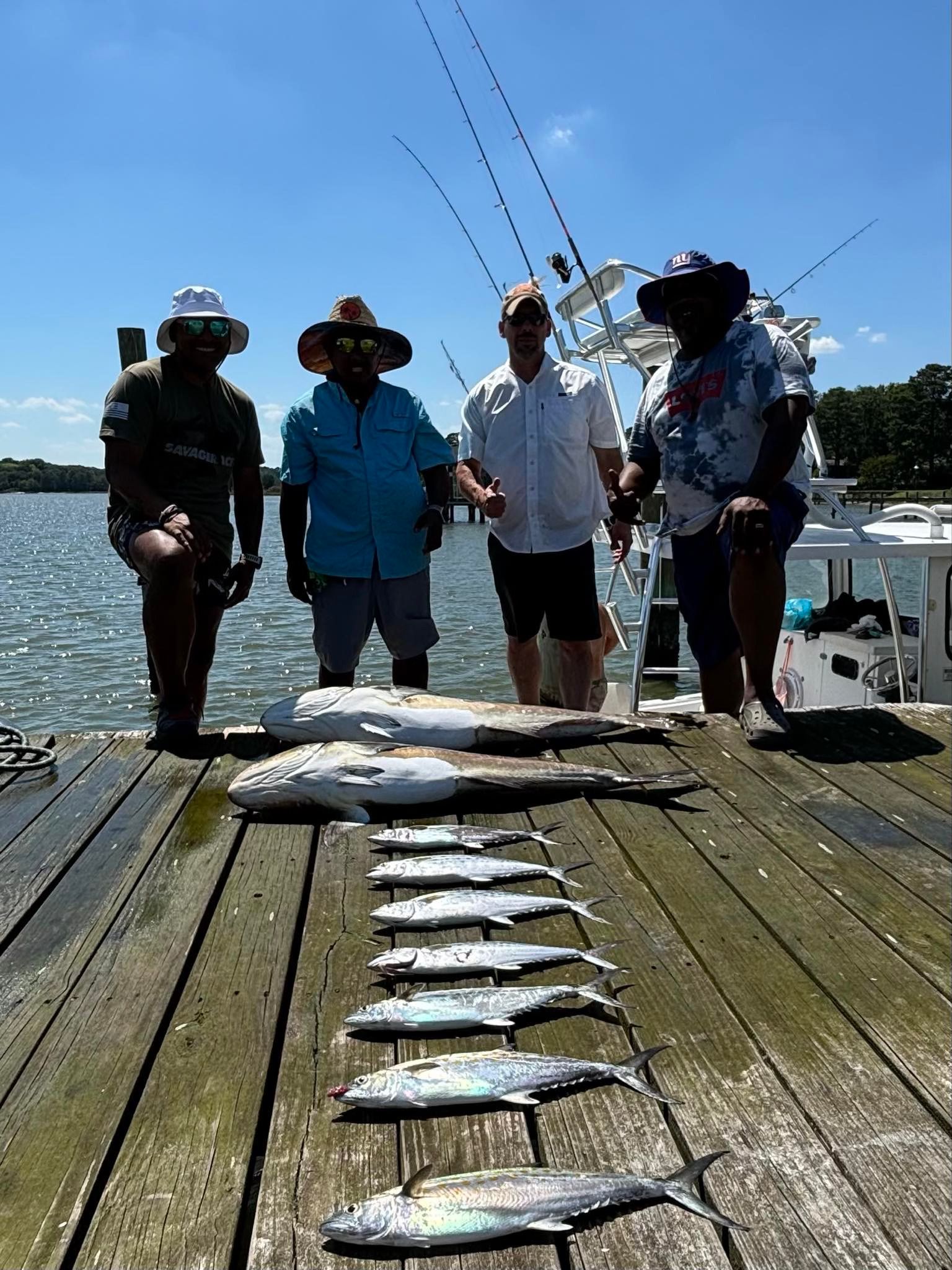 A group of men are standing on a dock holding fishing rods.