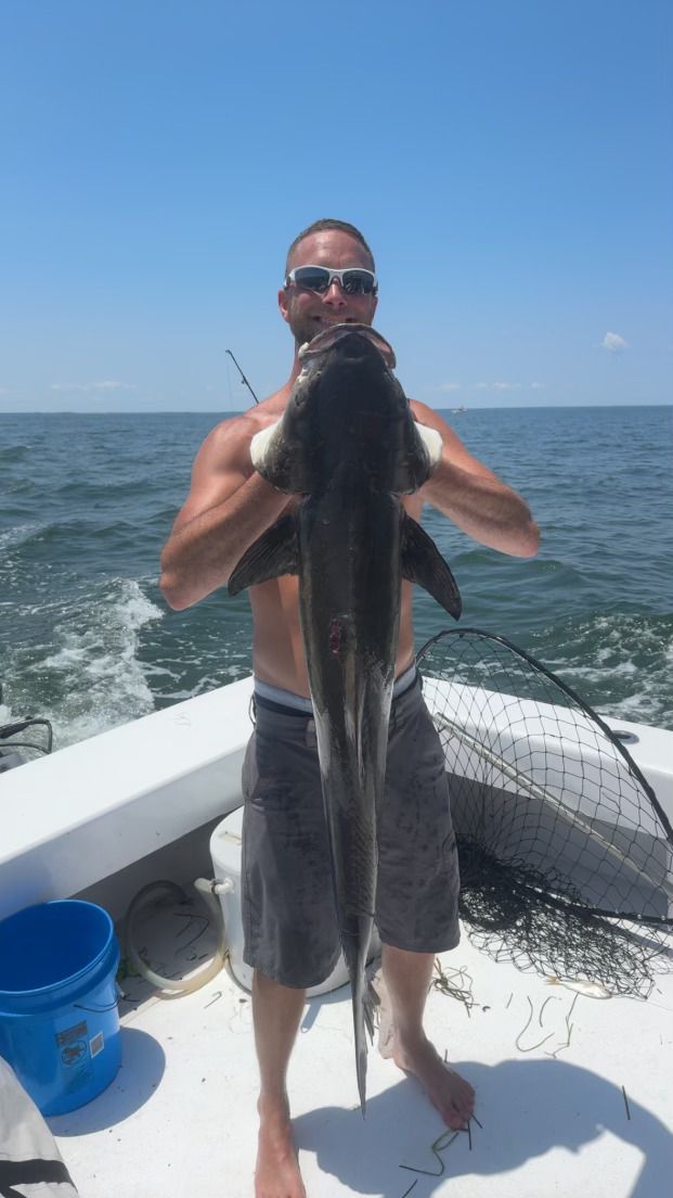 A man is holding a large fish on a boat in the ocean.