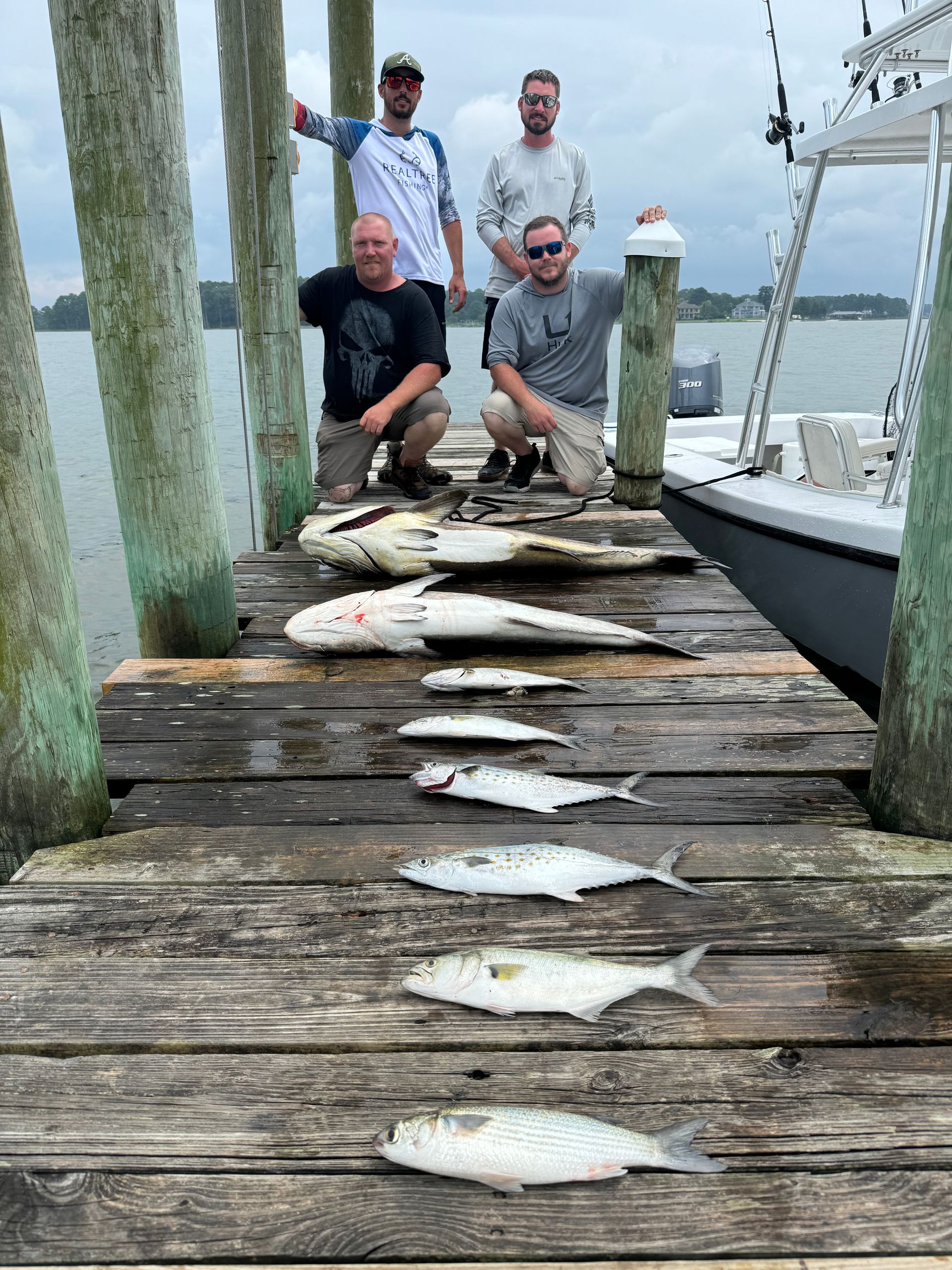A group of men are standing on a dock holding fish.