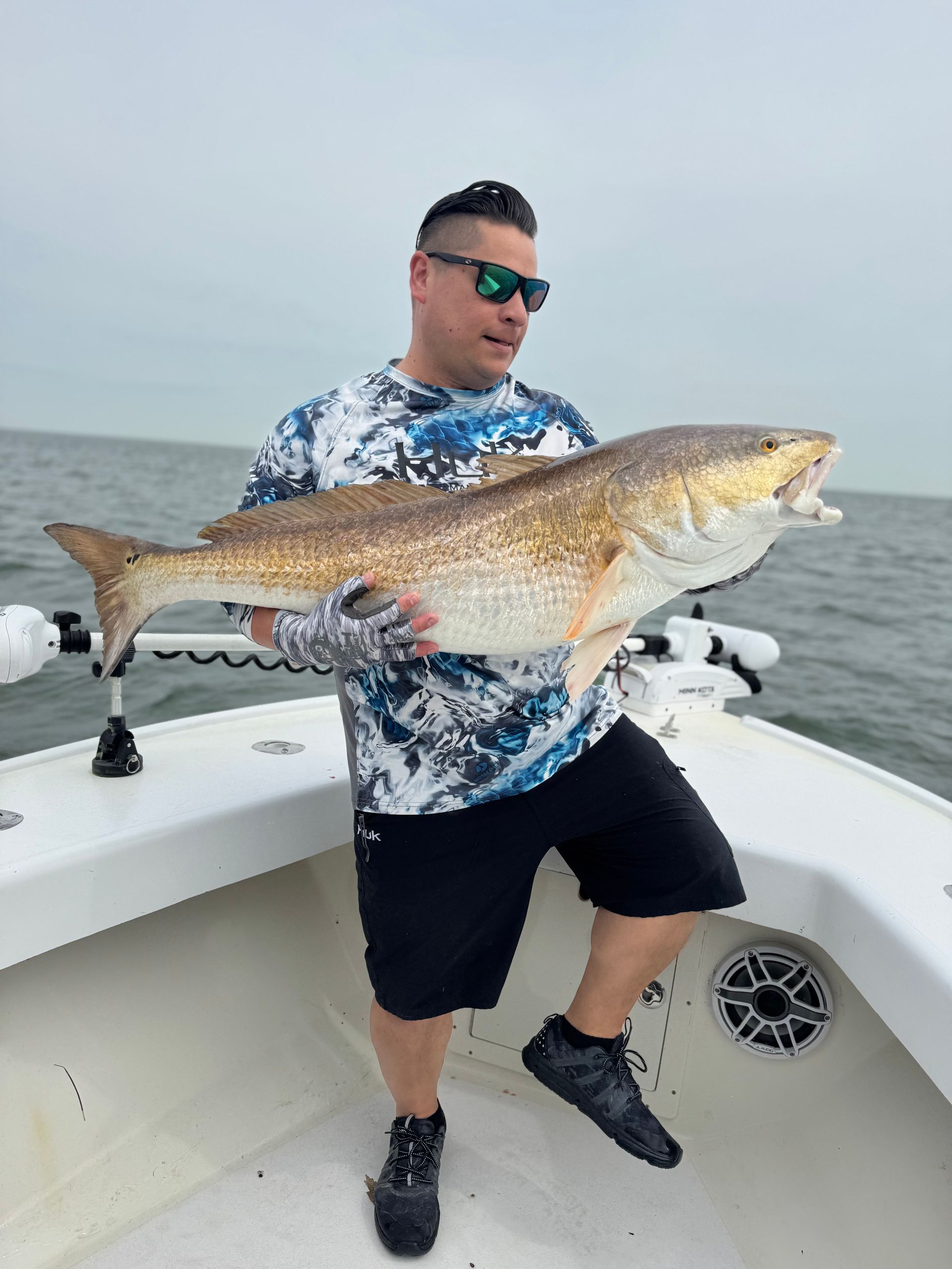 A man is holding a large fish on a boat.