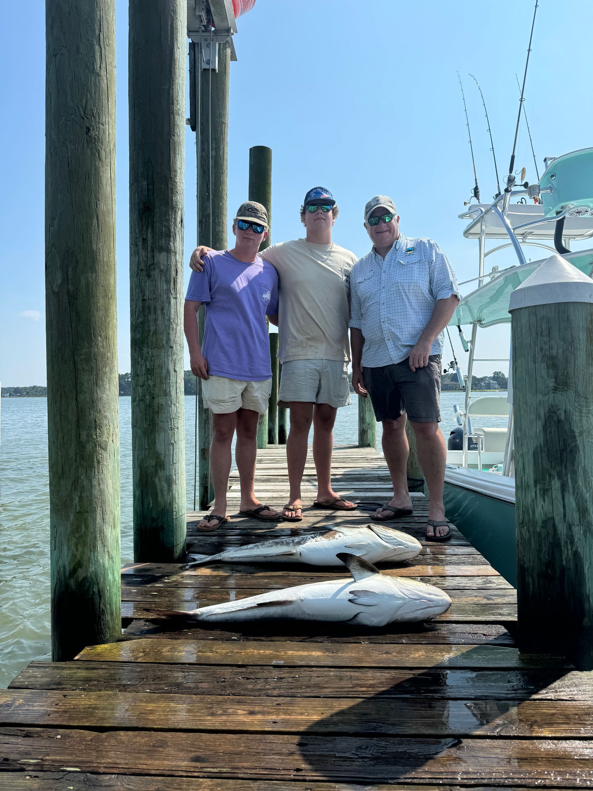 Three people are standing on a dock with fish on it.