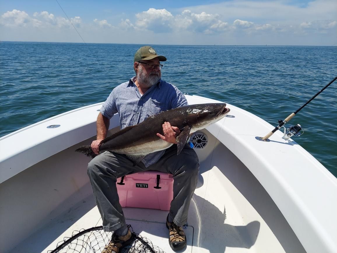 A man is sitting on a boat holding a large fish.