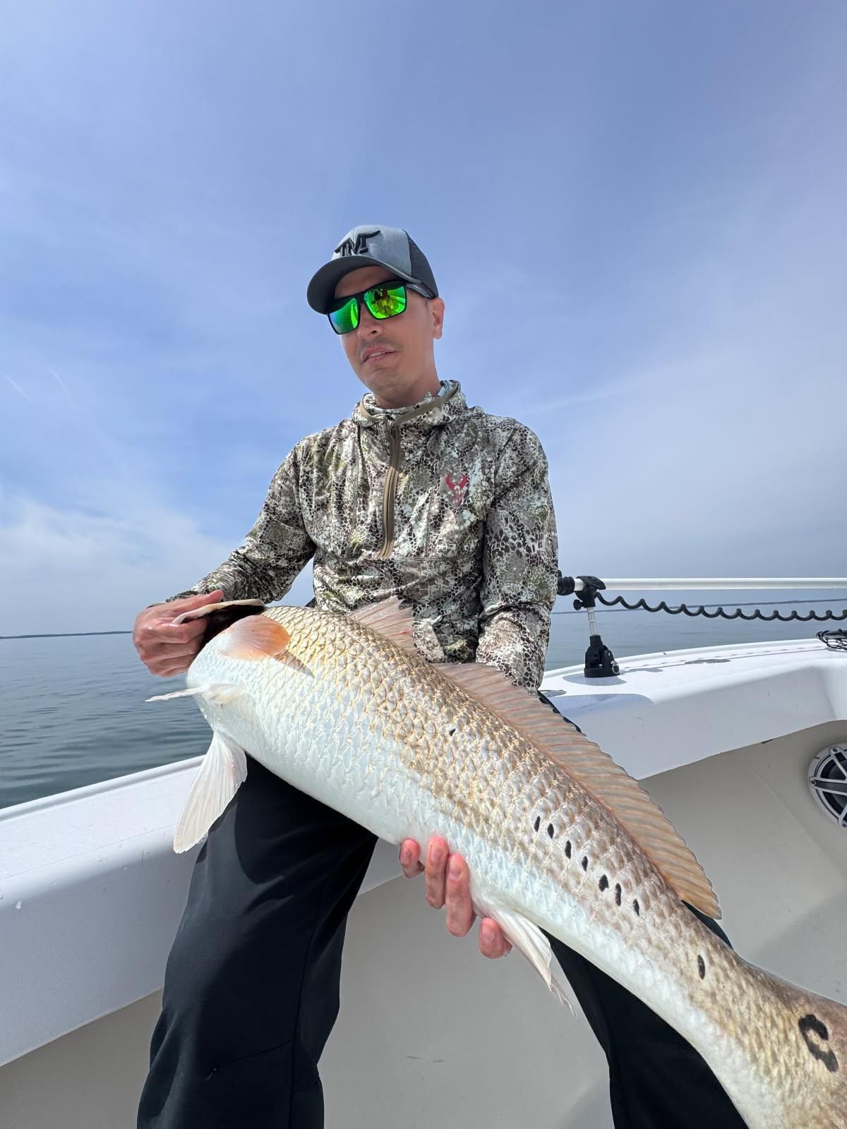 A man is holding a large fish on a boat.