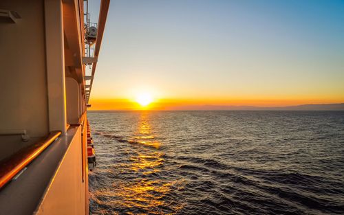 The sun is setting over the ocean from a cruise ship.