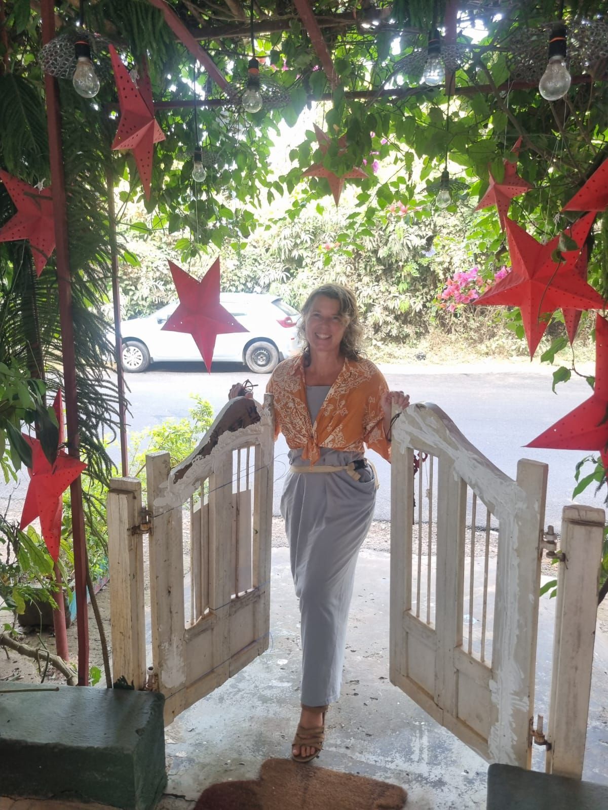 Woman in orange top and gray pants stands in doorway decorated with stars and vines. Rare Republic French Bakery and concept store.