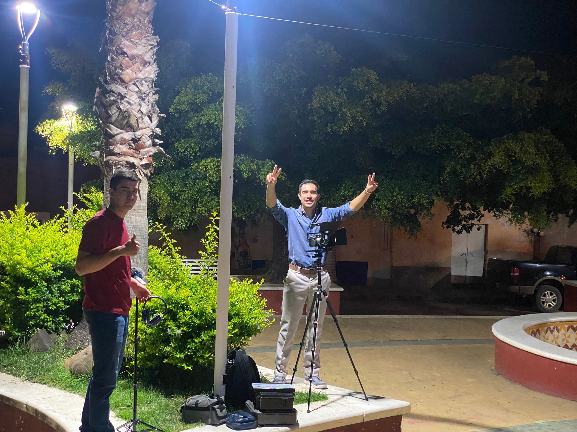 Dos hombres están parados uno al lado del otro en un parque por la noche.