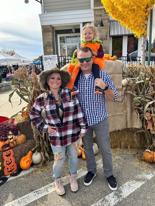 A man is carrying a little girl on his shoulders at a pumpkin patch.