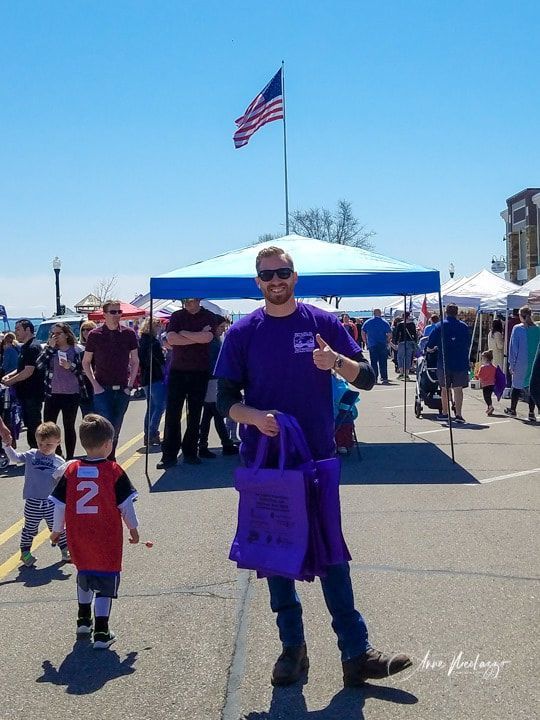 A man in a purple shirt is holding a purple bag