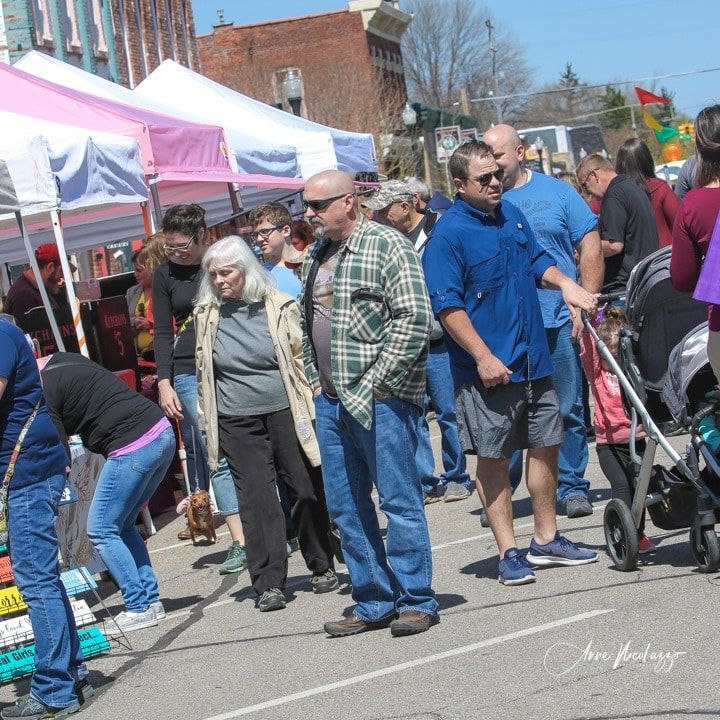 A crowd of people are gathered in a parking lot at a festival