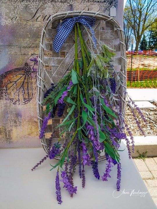 A basket filled with purple flowers is hanging on a wall