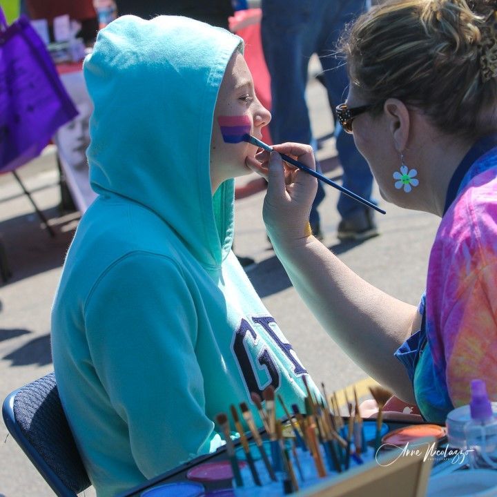 A woman is painting a girl 's face with a brush