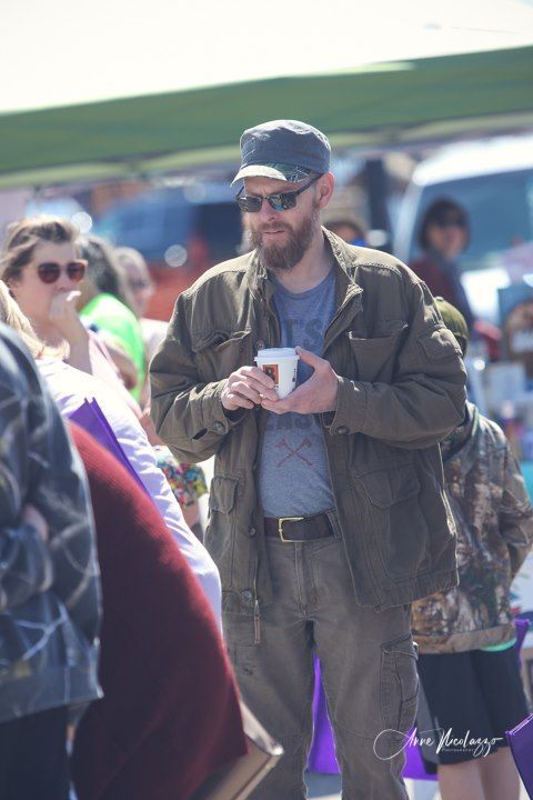 A man standing in a crowd holding a cup of coffee