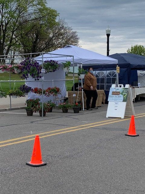 A man wearing a mask is standing in front of a tent with flowers on it