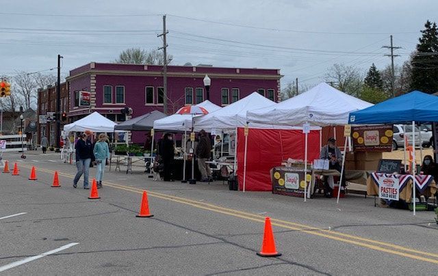 A group of people walking down a street with tents and cones
