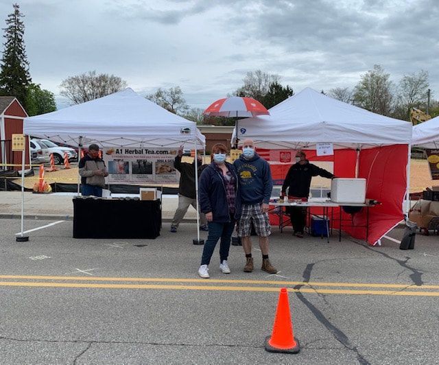 A group of people are standing in front of tents in a parking lot