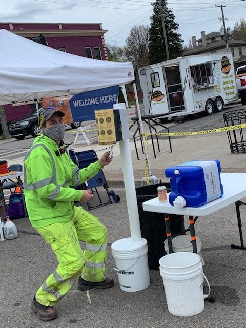 A man wearing a mask is standing in front of a welcome sign.