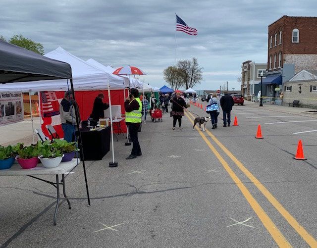 A group of people walking down a street with tents and cones
