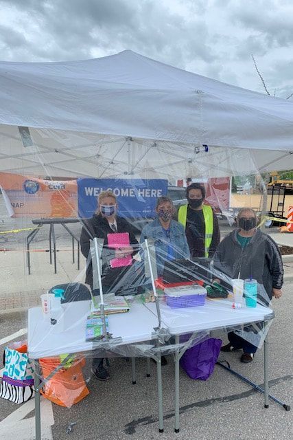 A group of people are standing around a table under a tent.