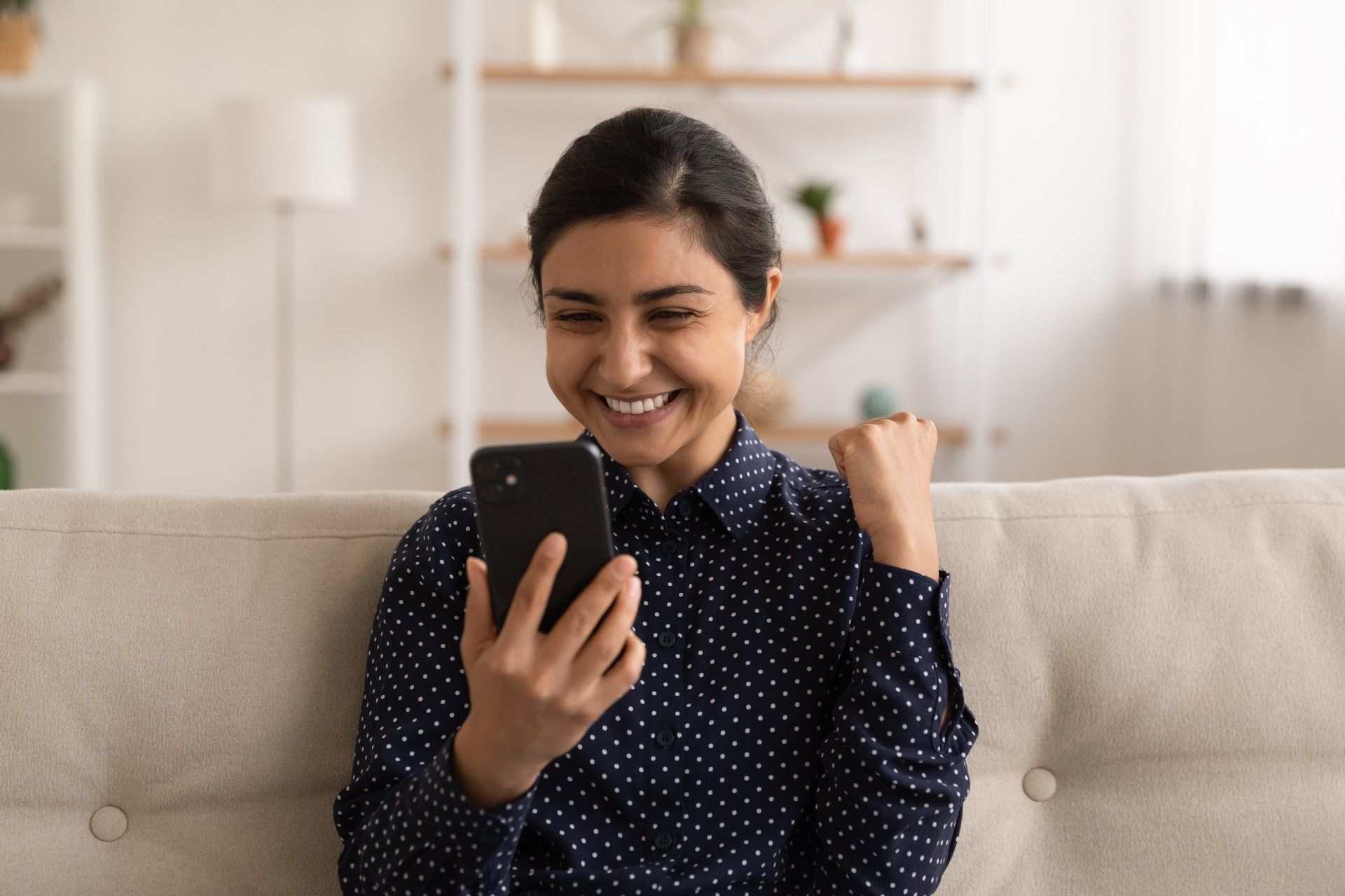 a woman is sitting on a couch looking at her cell phone