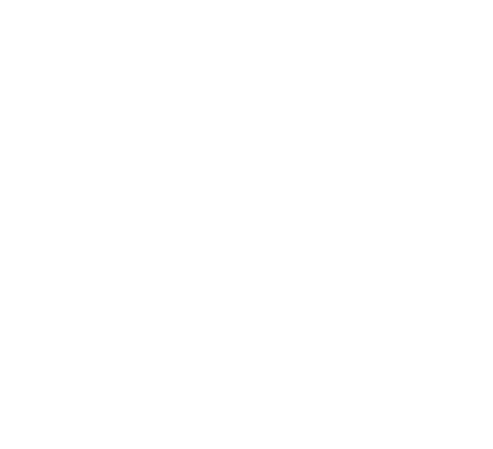 A person in a red uniform stands in a grassy field, using a handheld metal detector to search for items in the ground.