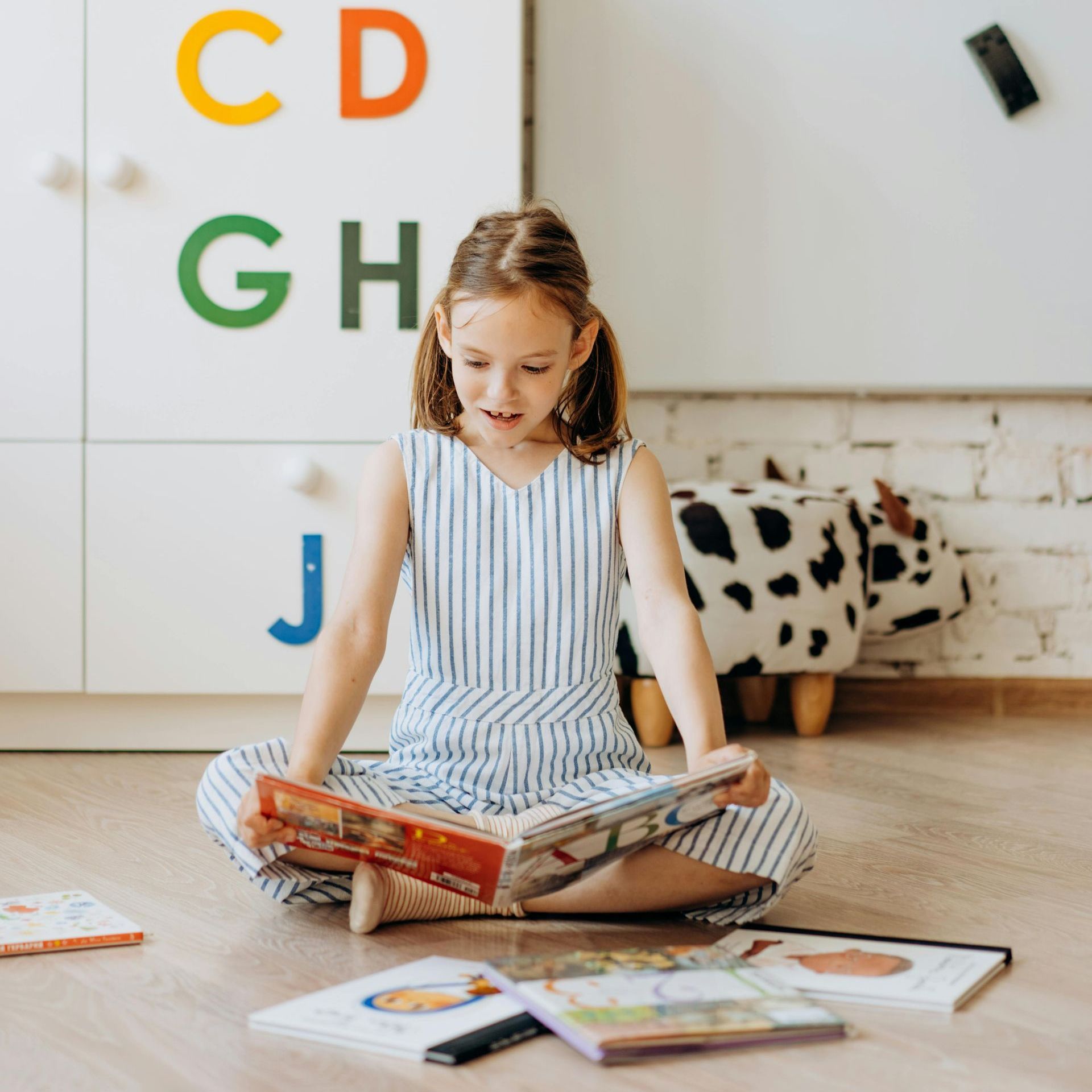A little girl is sitting on the floor reading a book