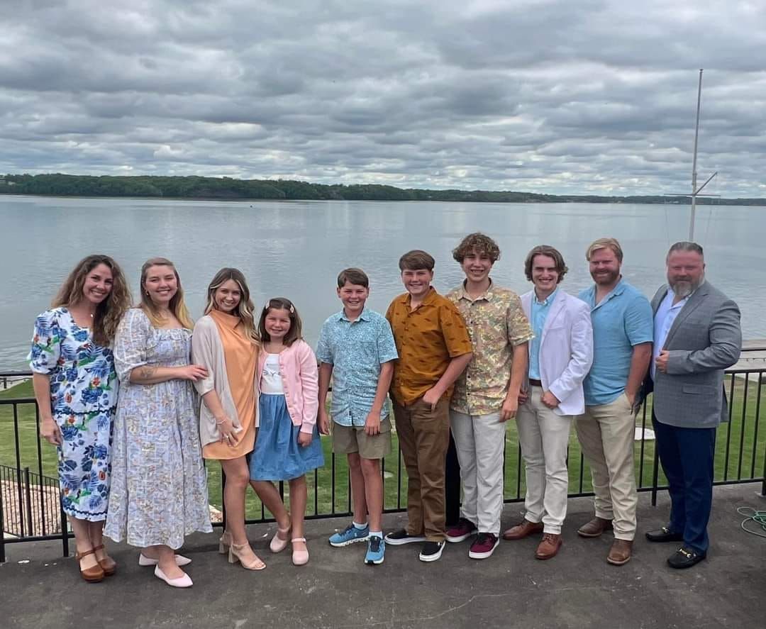 A group of people are posing for a picture in front of a body of water.