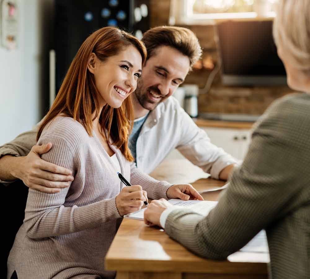 A man and a woman are sitting at a table signing a document.