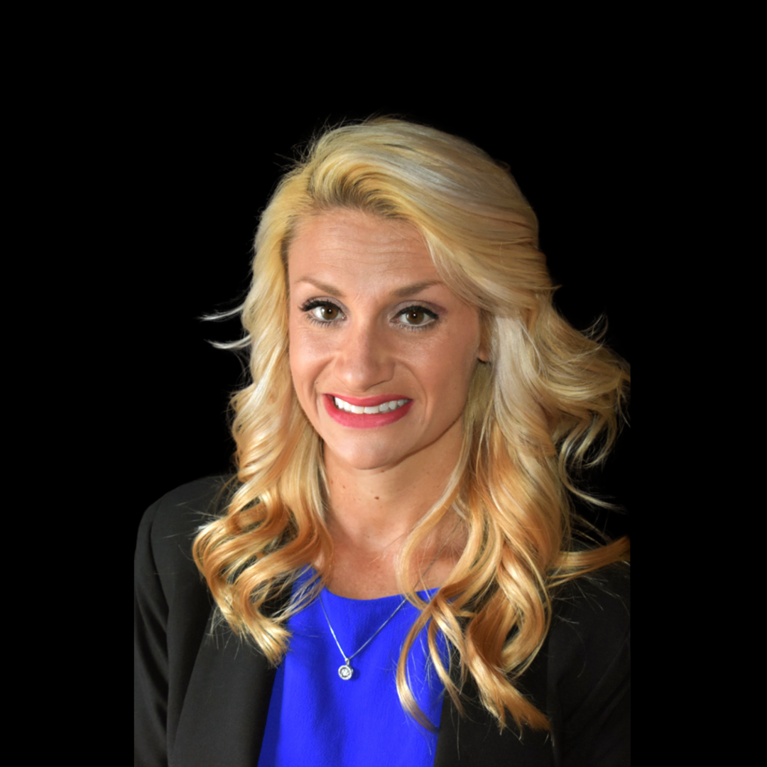 A woman with blonde hair is wearing a blue shirt and a black jacket.