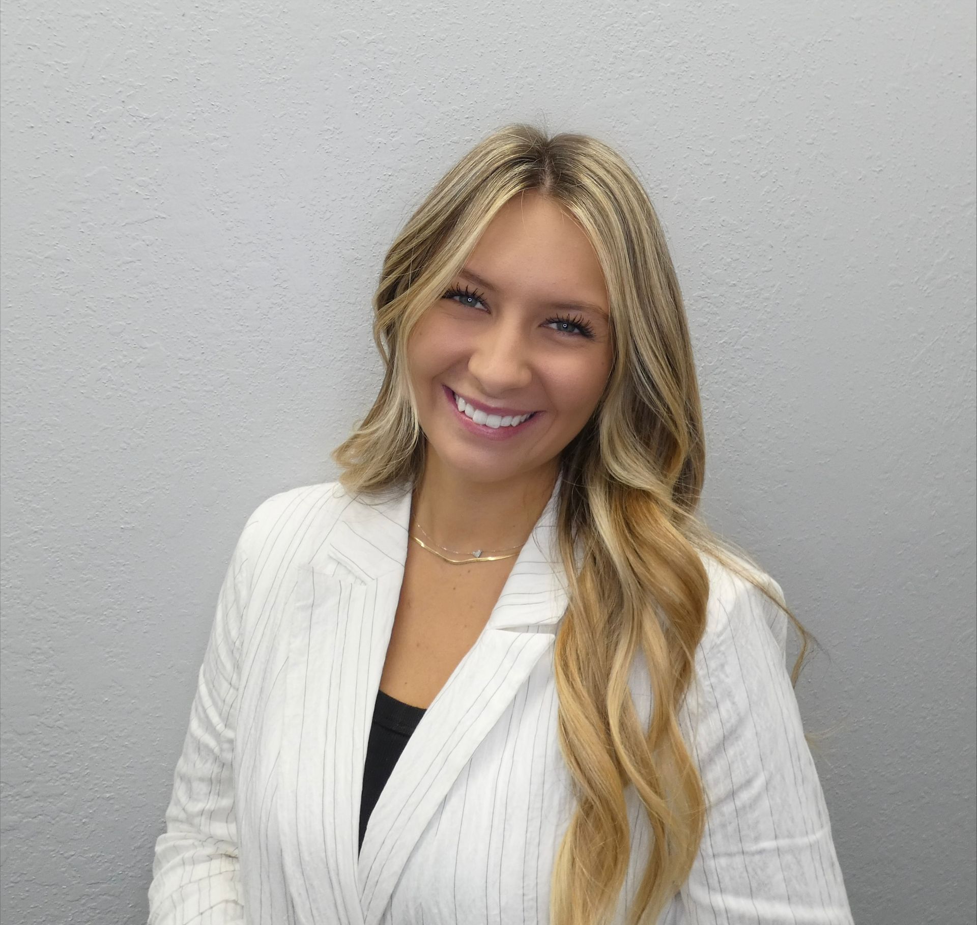 The woman is wearing a white jacket and smiling for the camera.